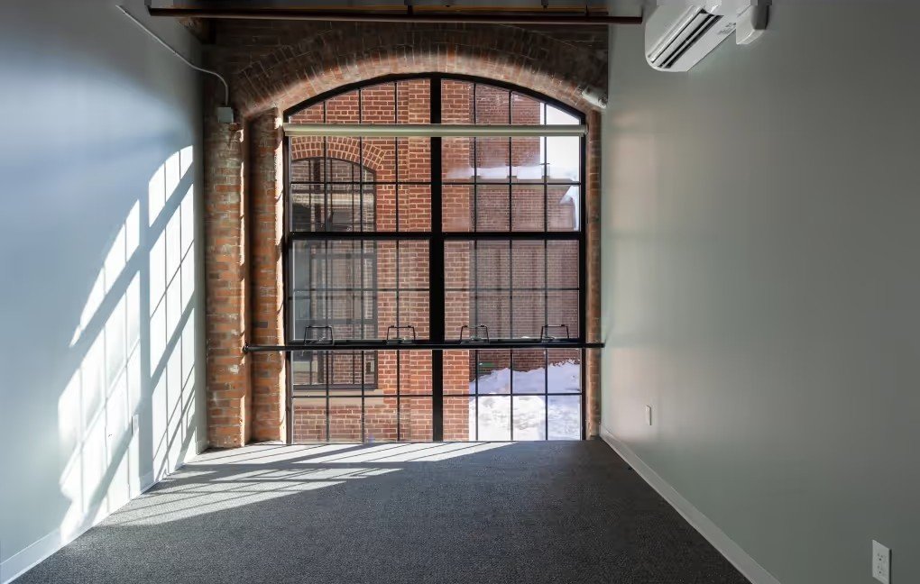 Bedroom with large arched mill window and mini-split head